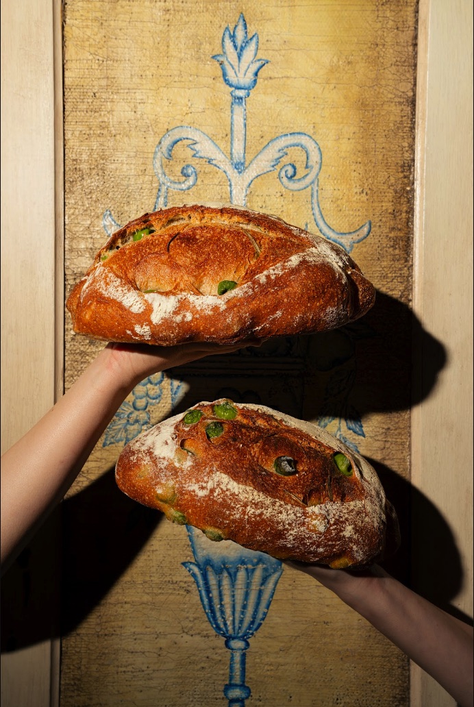 Two olive loaves held up, fresh from the oven